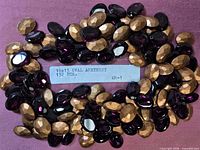 Bulk pile of faceted amethyst glass ovals with foil backs and label showing size and count
