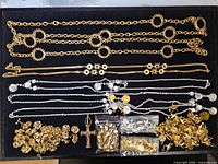Overview of all necklaces, chains, bags of findings and charms on black tray