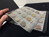 Album page partially lifted showing multiple coins in clear pockets