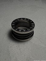 Angled view of pendant showing engraved BVLGARI lettering and ceramic center