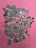 Spread of carved letter beads and cabochon beads on pink background