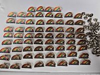 Front view of all 60 rainbow souvenir pins and separate clutch fasteners