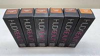 Six Huda Beauty foundation stick boxes lined up