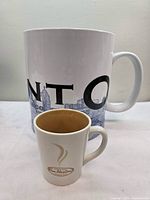 Front view of giant Starbucks Toronto Skyline mug with Tim Hortons demitasse for scale