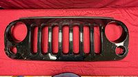 Front view of black Jeep Wrangler JK grille showing seven slots and headlamp openings
