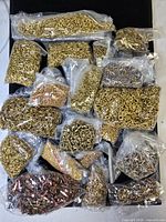 Multiple sealed plastic bags filled with metal grommets in assorted metallic colours