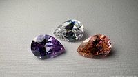 Three pear-cut gemstones on fabric surface