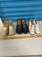 Three pairs of women’s slip-on shoes side by side with ruler for scale