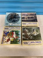 All four sealed Bits and Pieces puzzle boxes front view