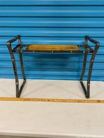 Full view of metal frame bench with wood seat and measuring tape