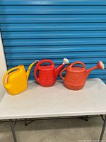 Group shot of three watering cans on table