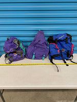 Front view of all three Nikko backpacks with measuring tape for scale