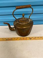 Left side view of copper tea kettle beside ruler