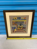 Front view of framed needlepoint showing full artwork and measuring tape indicating width ~17 in.