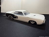 Left front and side view of 1/24 scale Cuda slot car showing body, wheels, and wheelie bar