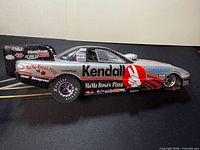 Left side view of the Kendall-liveried funny car showing sponsor decals and wheelie bar