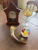 Group shot of all four items: wooden clock, horn, paperweight, amber crystal glass