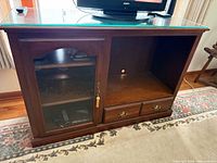 Front view showing overall cabinet, glass top, glass door, open section, drawers