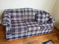 Full view of plaid sleeper sofa with cushions and pillow