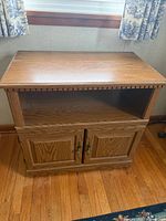 Front view of oak TV stand showing top, open shelf, and closed double doors