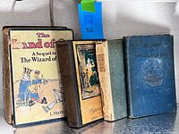 Four hardcover books standing: Land of Oz, Pinocchio, The Piper, Snubs Our Dog