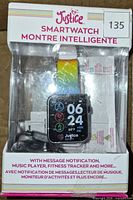 Front view of boxed Justice smartwatch with rainbow band, cable and paperwork