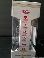 Side of box showing Justice logo and function icons (heart rate, pedometer, music player, etc.) with watch visible inside