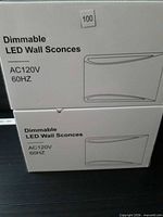 Front view of two sealed sconce boxes showing product name and voltage