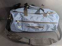 Full view of blue gym bag showing handles, strap, front pocket