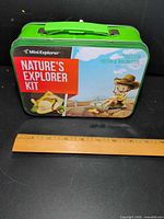 Front view showing graphics, handle, latch, ruler indicating width ~9 in