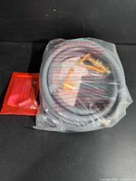 Coiled 12-ft grey NG hose with brass fittings and red pouch of jets in plastic bag