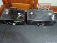 Both black steamer trunks side by side