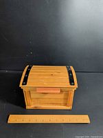 Closed wooden chest beside ruler showing size under 12 inches
