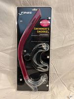 Front of packaged Finis swimmer’s snorkel showing red tube and clear mouthpiece