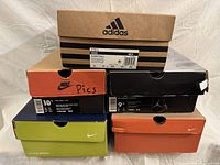 Stack of five shoe boxes showing brands and colours