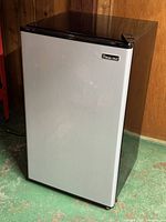 Front view of Magic Chef compact refrigerator showing stainless front and black sides