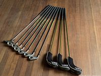 Seven Adams Idea irons and three hybrids laid out showing grips and shafts