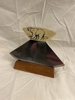 Ulu knife inserted into wooden stand, polar bear decoration visible