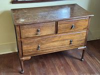 Front view showing three drawers, brass pulls, turned legs