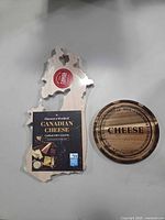Canada shaped board with packaging beside round board showing engraved side