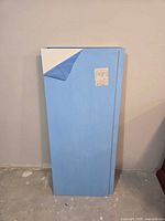 Stack of four MDF panels with blue protective film showing white surface underneath