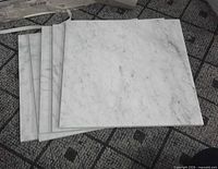 Stack of five marble tiles showing polished surfaces and veining