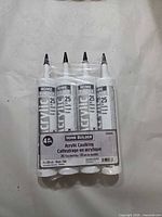 Front view of sealed 4-pack acrylic caulking tubes