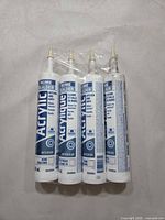 Four sealed tubes of acrylic caulk standing together