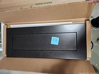 Top view of one midnight black Cutler cabinet door inside original packaging