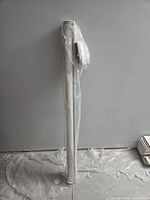 Rolled electric blind in plastic wrap standing vertically