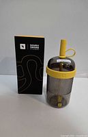 Tumbler with straw alongside original black retail box