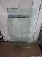 Full view of rectangular glass tabletop showing metal mounting bars and screws