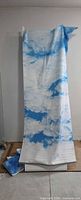 Full-length view of one sky backdrop fabric draped over stand, smaller panels at base