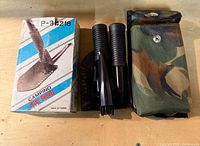 Box, disassembled shovel handle sections, camo pouch